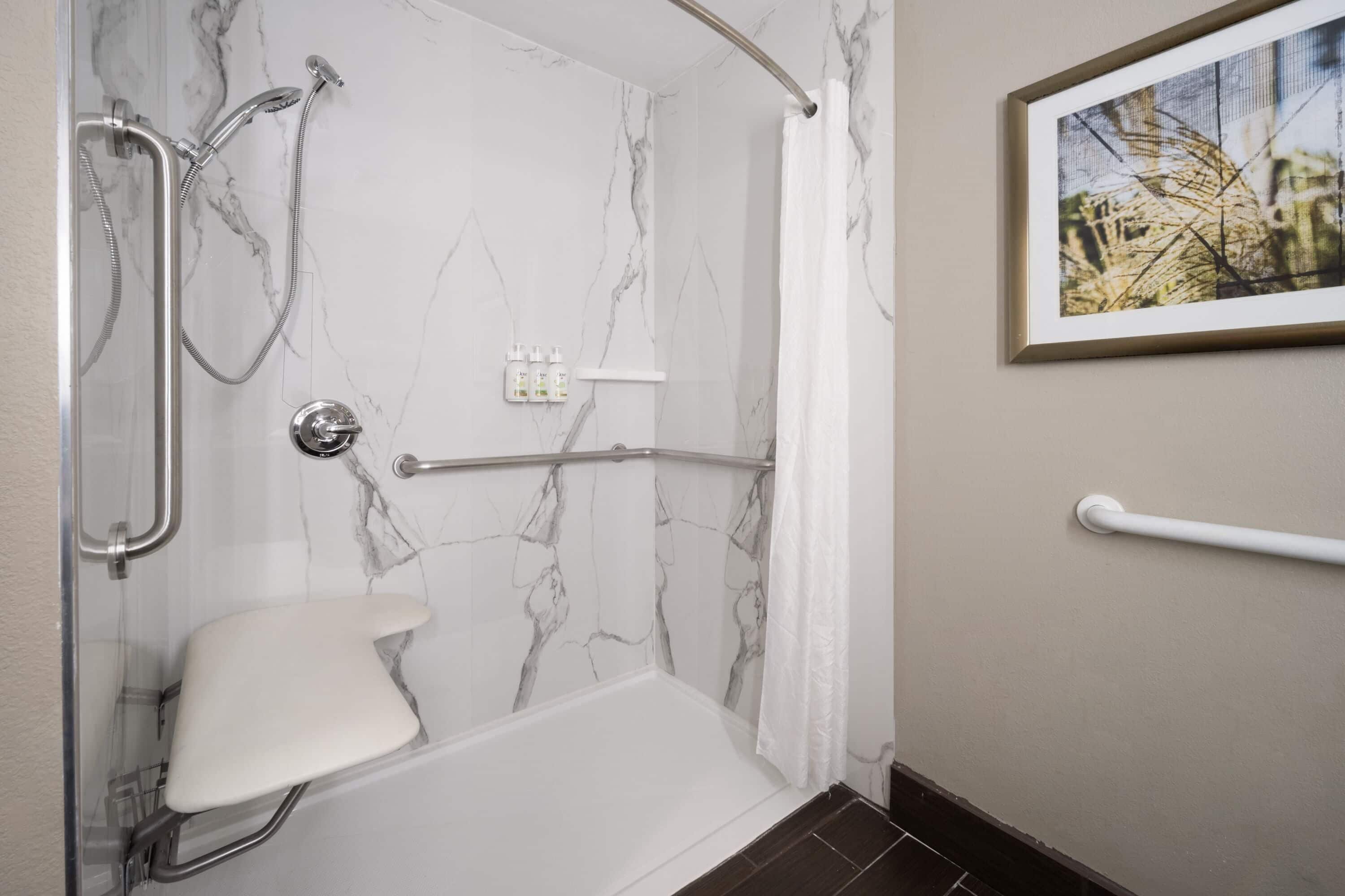 Une salle de bain équipée d’une douche, de toilettes et de barres d’appui.