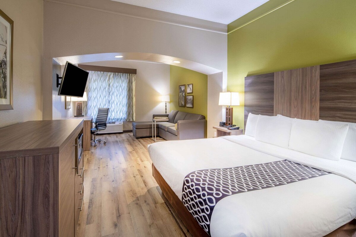 A hotel room with a bed, desk, chair, and a television.