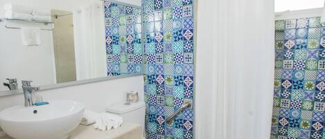 Un baño con lavamanos blanco, inodoro y cortina de ducha.