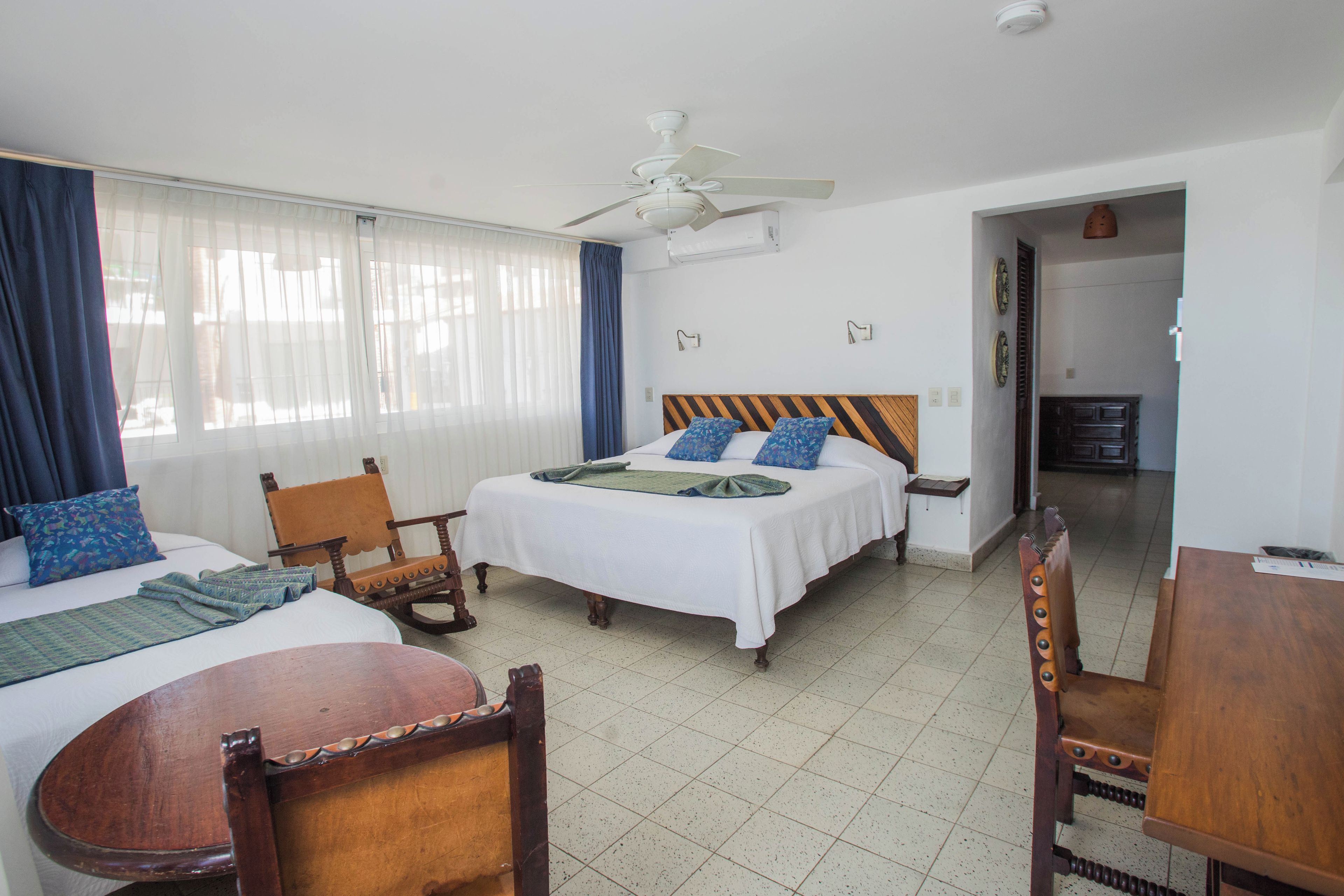 Una habitación de hotel con cama, una silla, una mesa y un ventilador de techo.