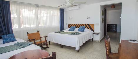 Una habitación de hotel con cama, una silla, una mesa y un ventilador de techo.