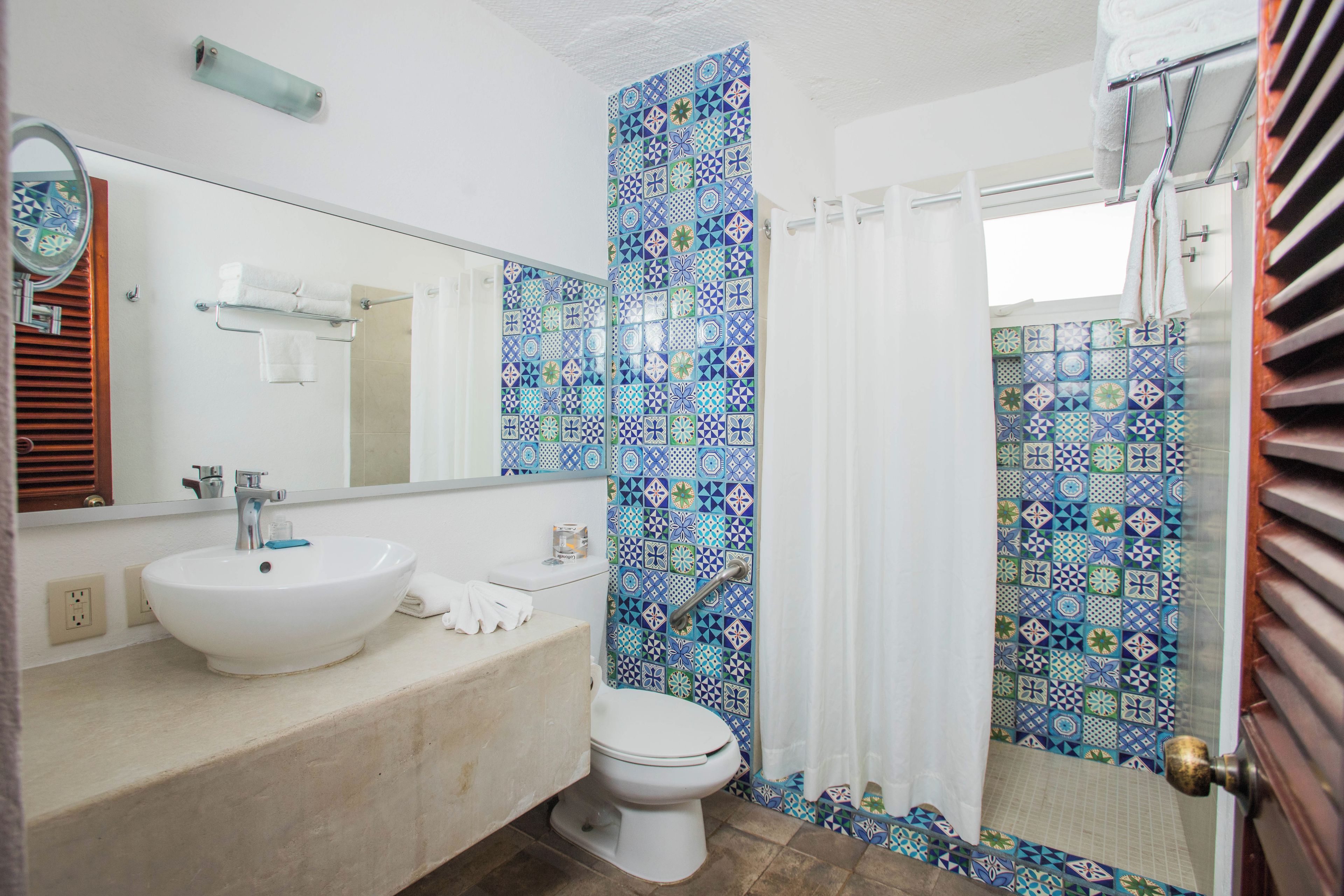 Une salle de bain avec un lavabo blanc, des toilettes et un espace douche.