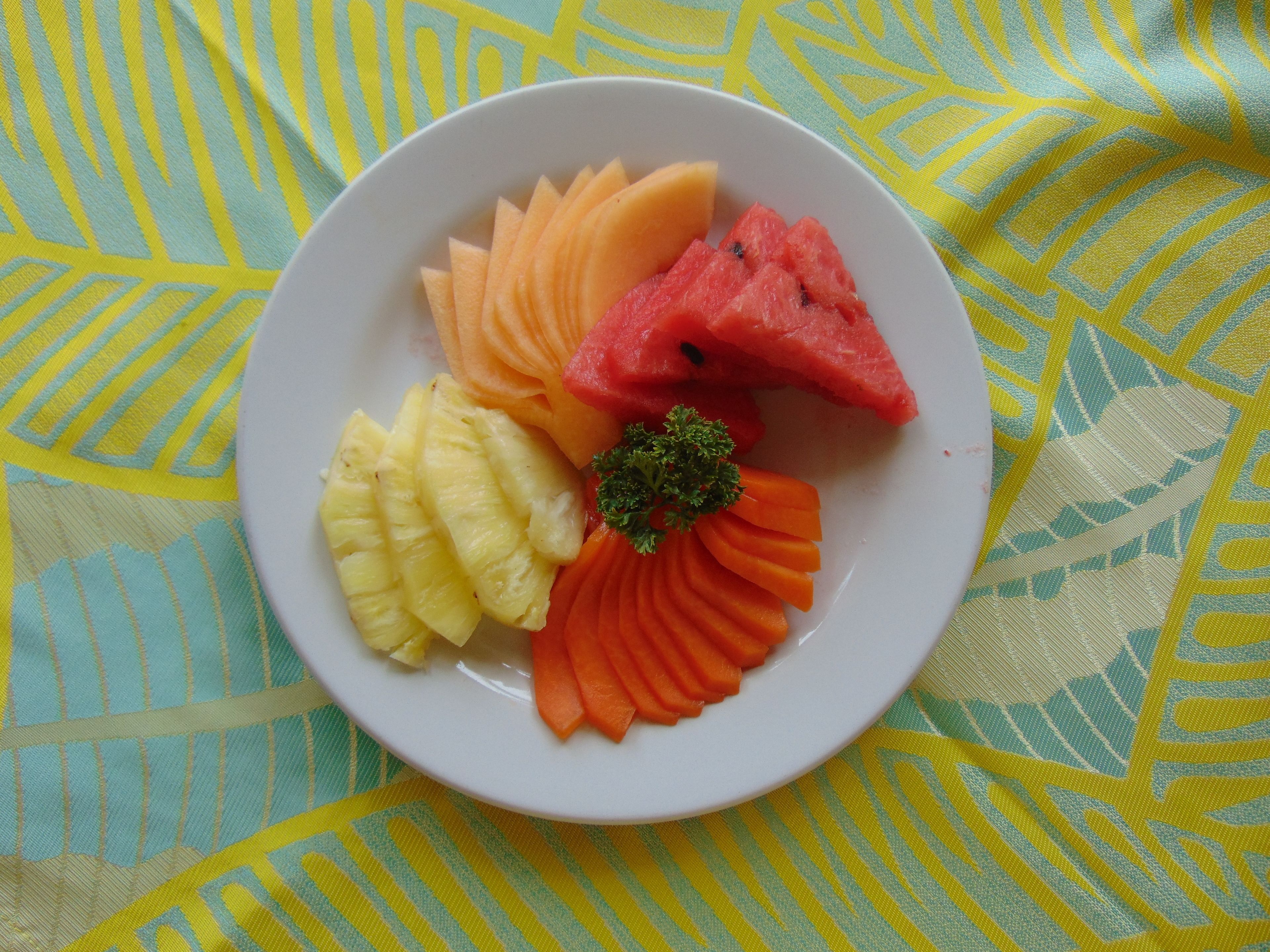 A plate with sliced watermelon, pineapple, and carrots.