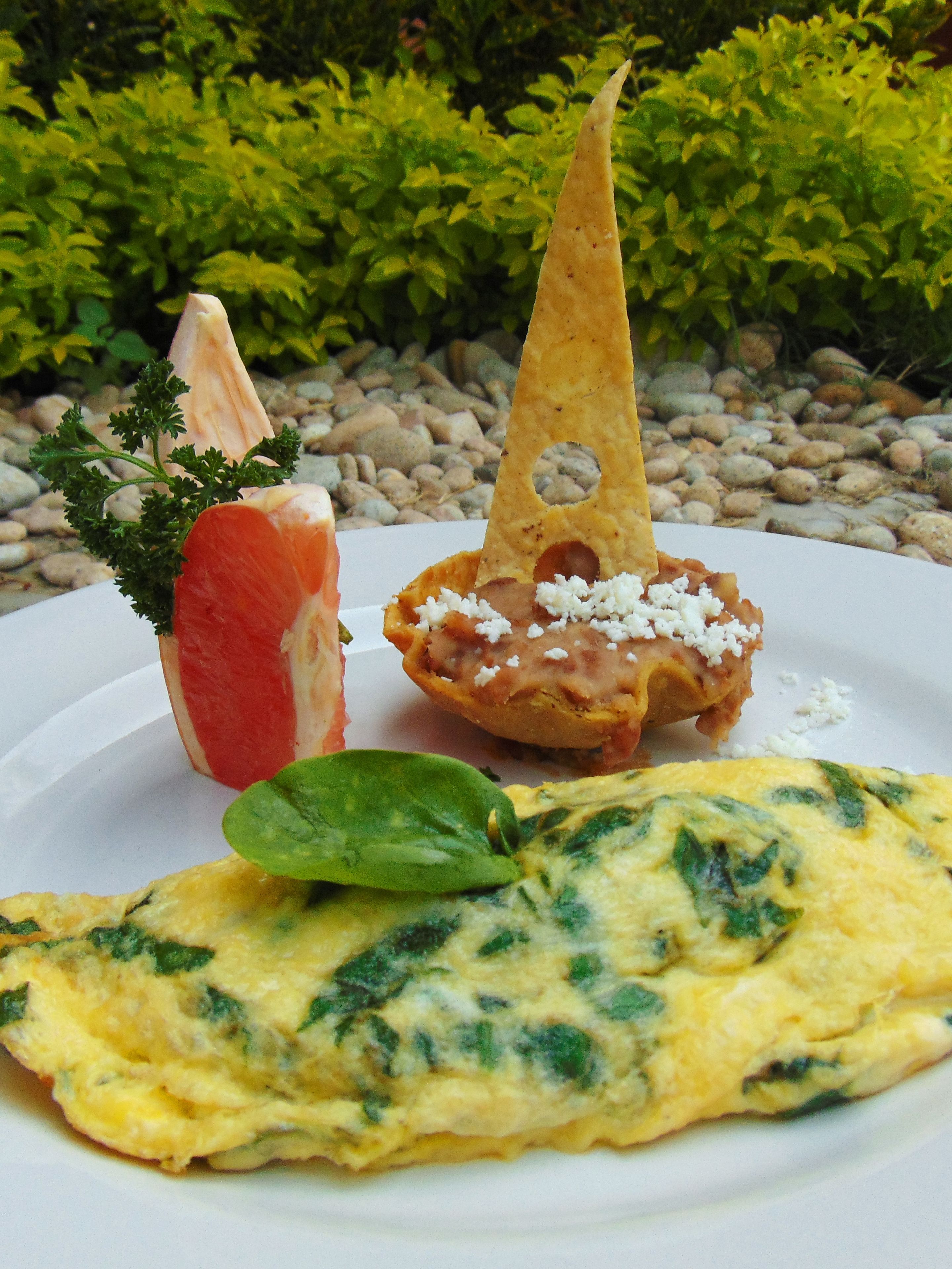 Une assiette contenant une omelette, une tranche de tomate et une tranche de pain garnie de fromage.
