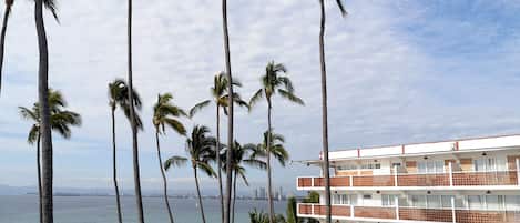 Un hotel frente al mar con varios pisos, palmeras y vista al océano.