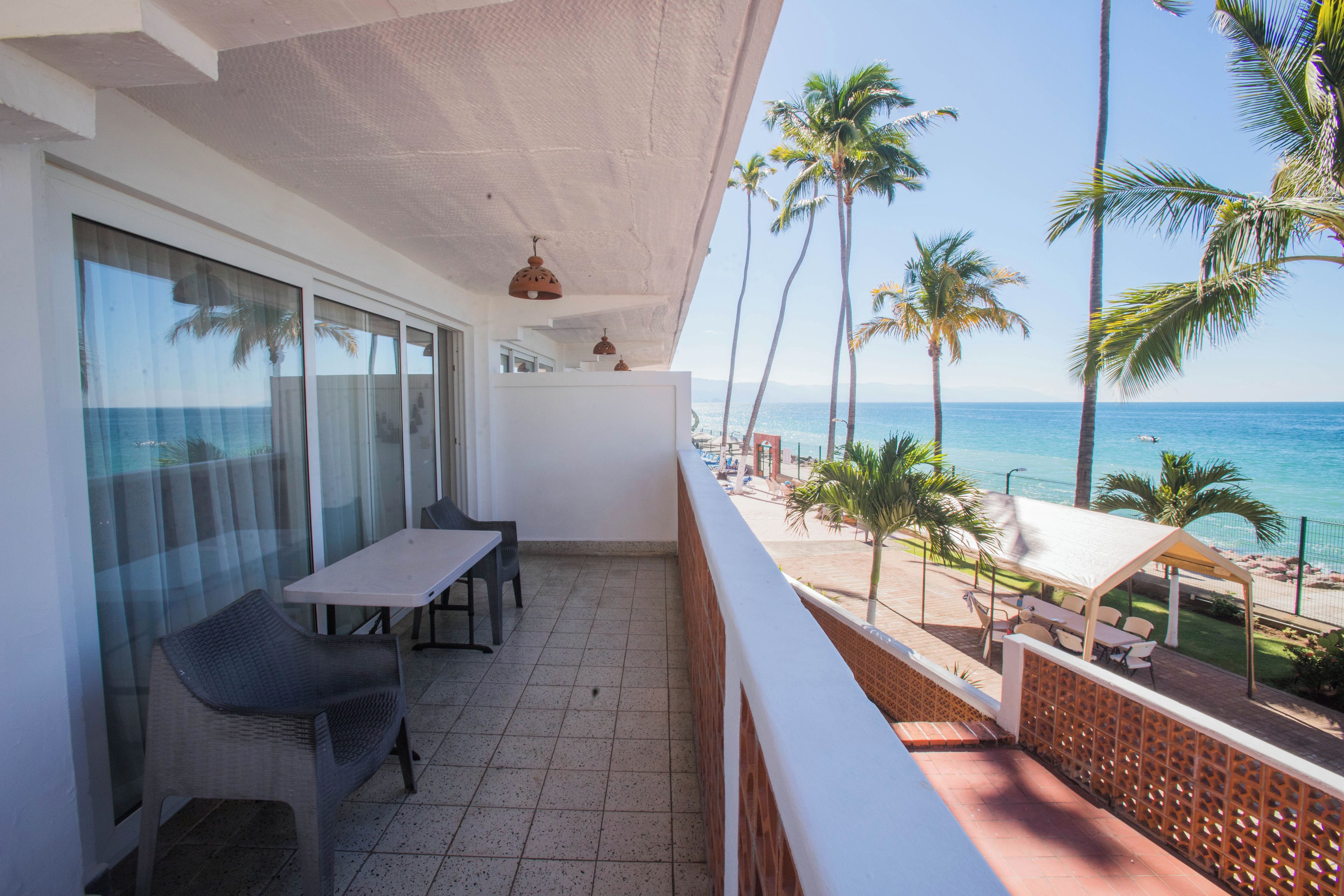 Een balkon met uitzicht op de oceaan, een tafel, stoelen en een hekwerk.