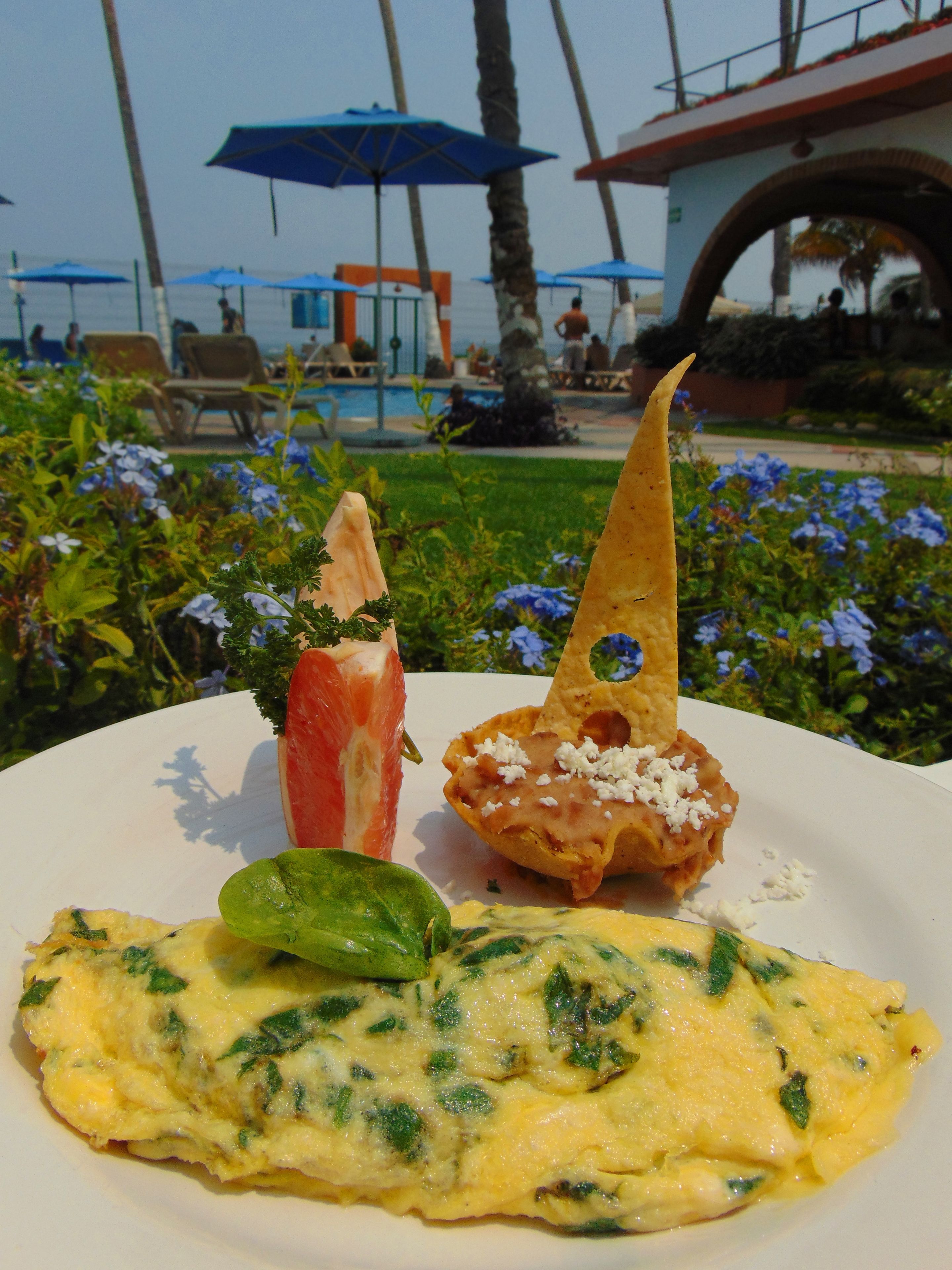 A plate with an omelette, a slice of tomato, and a piece of bread with cheese.