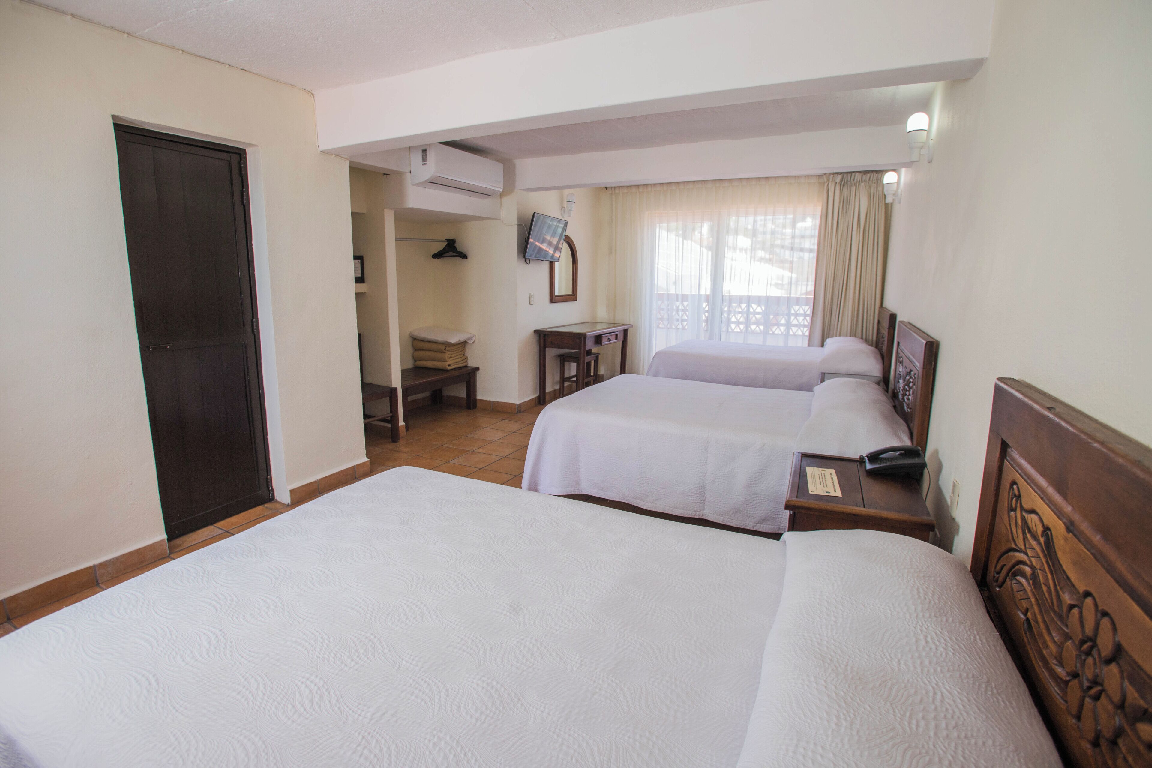 Une chambre d’hôtel avec deux lits, un bureau, une chaise et un appareil de climatisation.