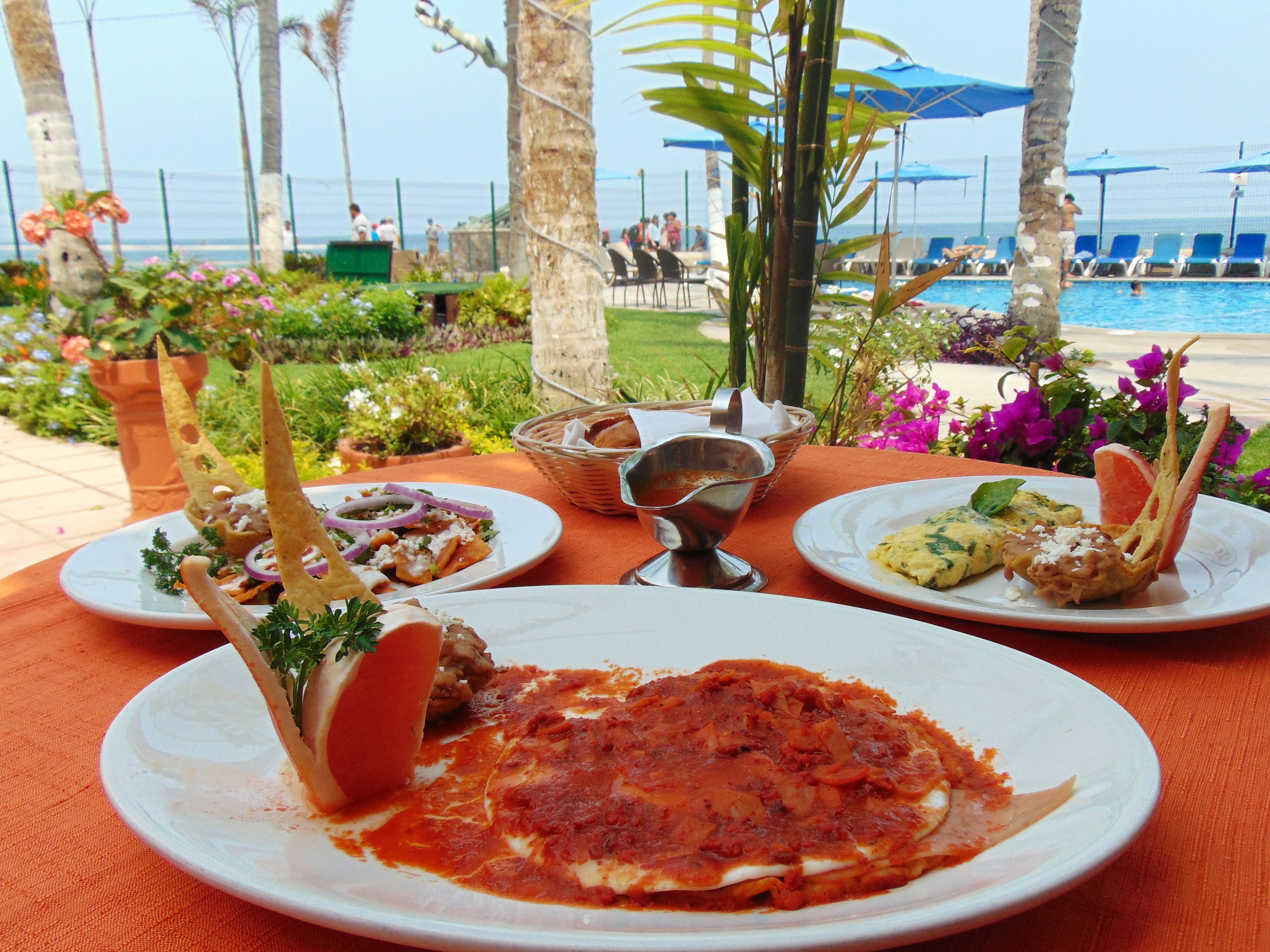 Una mesa con platos de comida, una piscina y vista al océano.