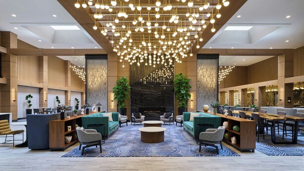 Un hall d’entrée spacieux, agrémenté d’un lustre moderne, de coins salon et d’un comptoir d’accueil.