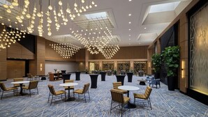 Un hall d’hôtel spacieux, doté de plusieurs espaces salon, d’un grand lustre et d’un design moderne.