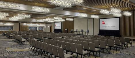 Sala de conferência com fileiras de cadeiras, uma tela grande e várias luminárias de cristal.