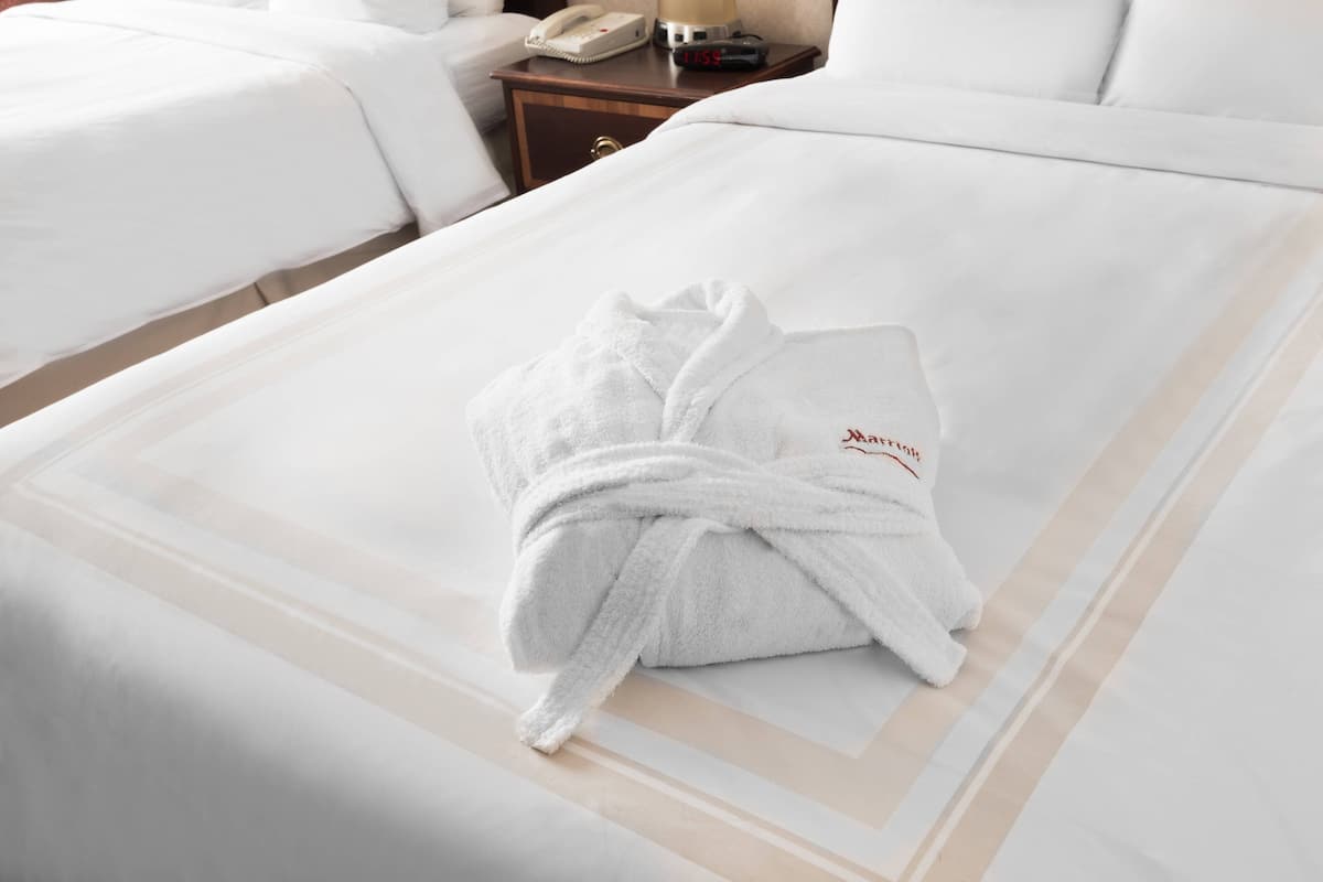 A hotel room with a neatly made bed, a bedside table with a lamp, and a telephone.
