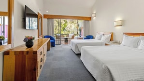 A hotel room with two beds, a wooden dresser, a TV, and a balcony with a view of greenery. - Hotel Rancho San Diego Grand Spa Resort (Ixtapan de la Sal)