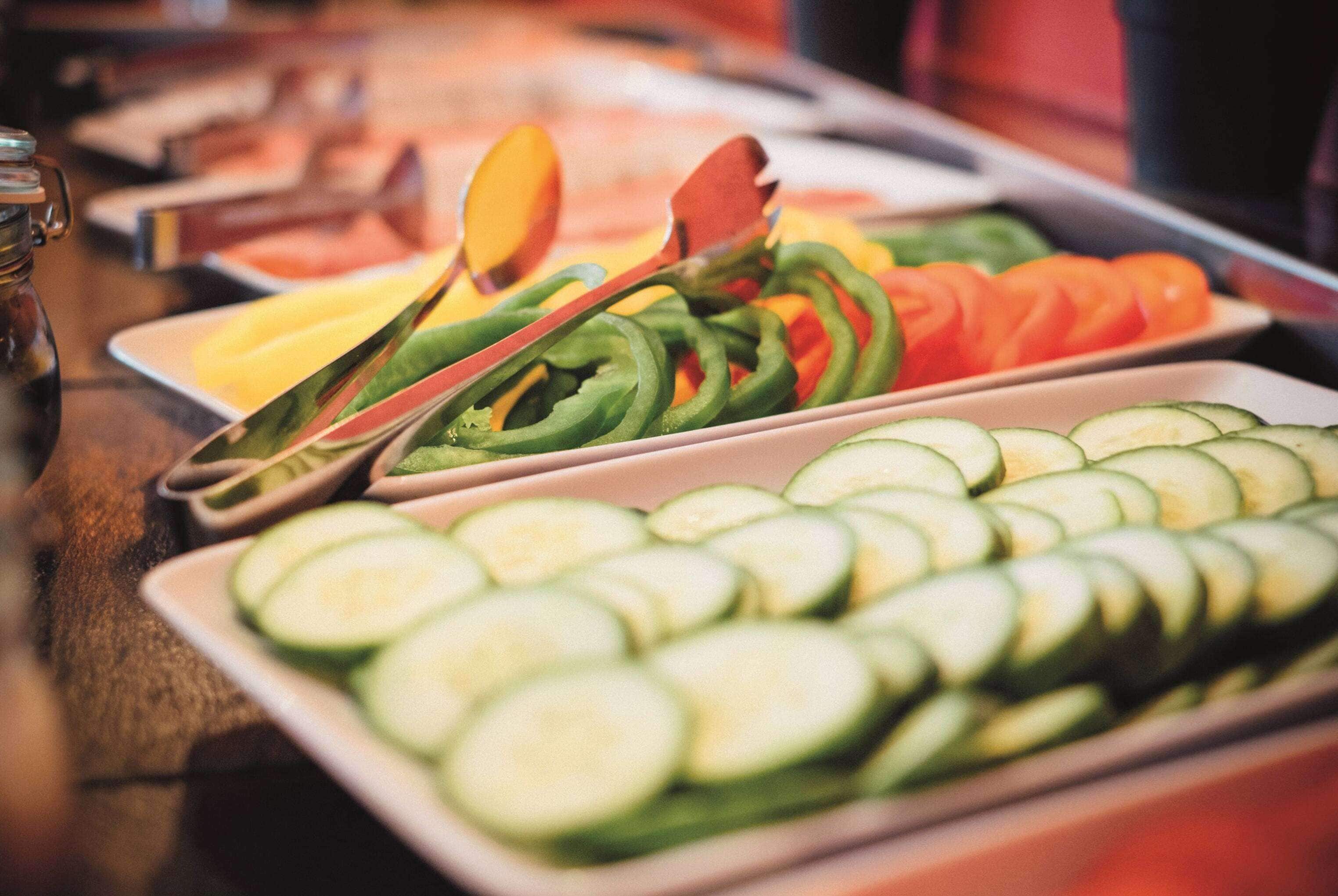 A buffet table with various sliced vegetables.