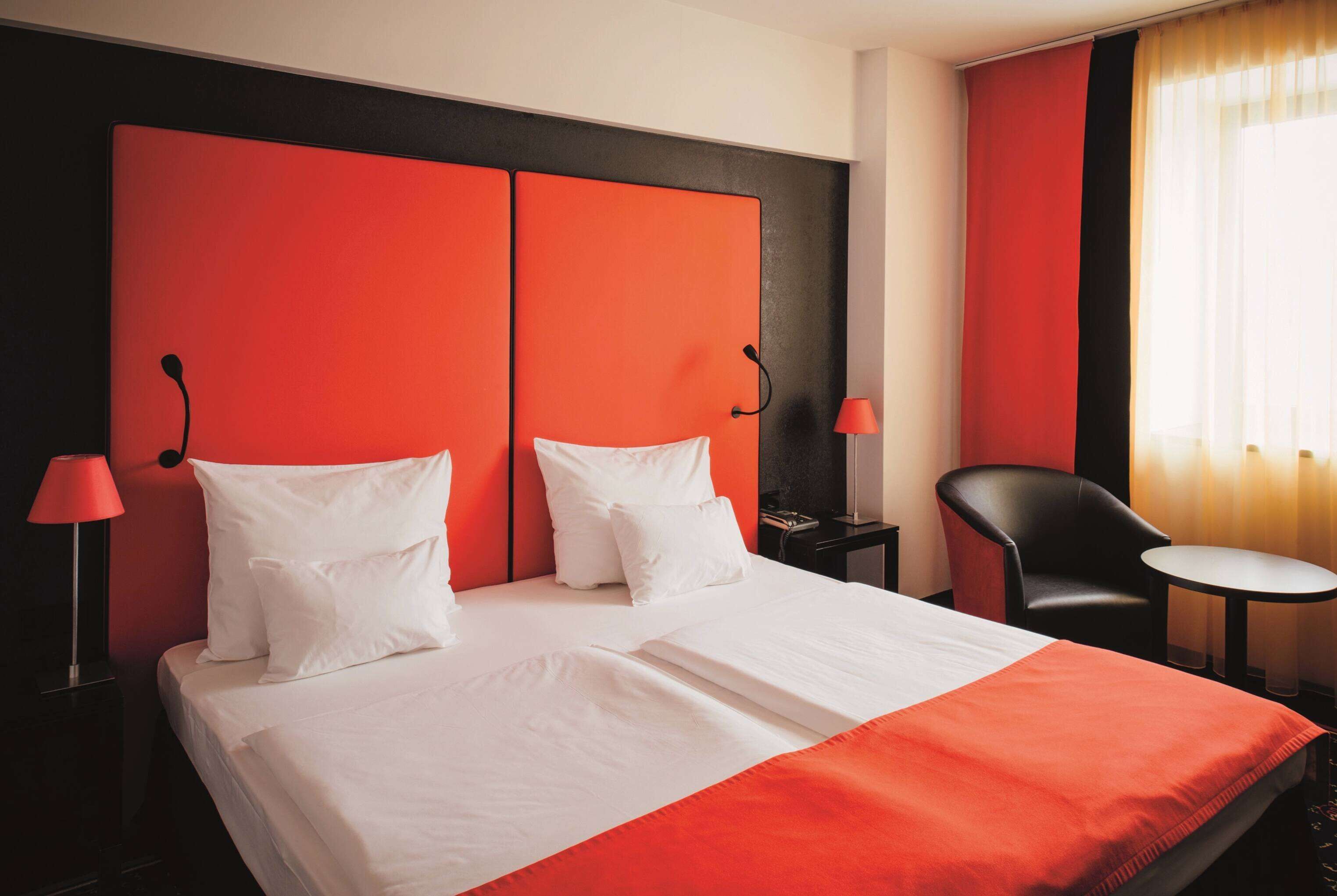 A hotel room with a large bed, two bedside tables, a chair, and a small table.