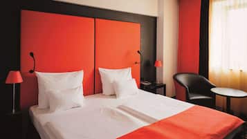 A hotel room with a large bed, two bedside tables, a chair, and a small table.