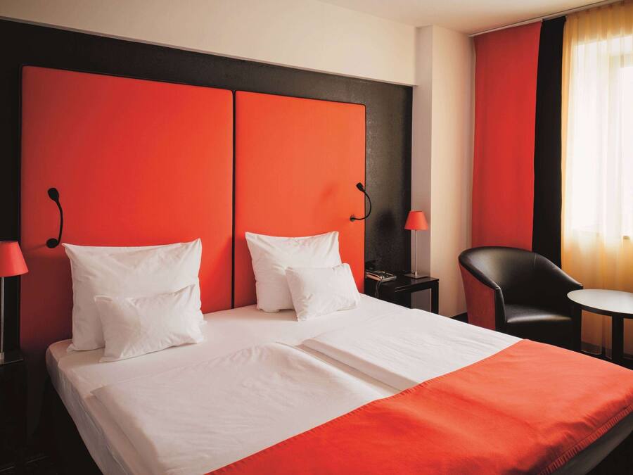 A hotel room with a large bed, two bedside tables, a chair, and a small table.