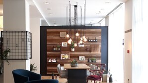 Un intérieur moderne avec un espace salon central, un mur lambrissé en bois, des luminaires suspendus et un plafond doté d’un éclairage encastré.