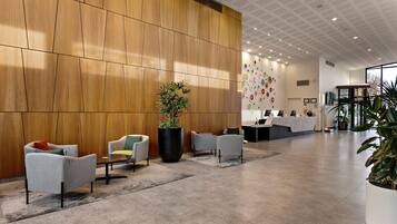 A modern reception area with a wooden panel wall, a reception desk, and several seating areas with chairs.