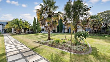 A well-maintained garden with a stone pathway leading to a building entrance.