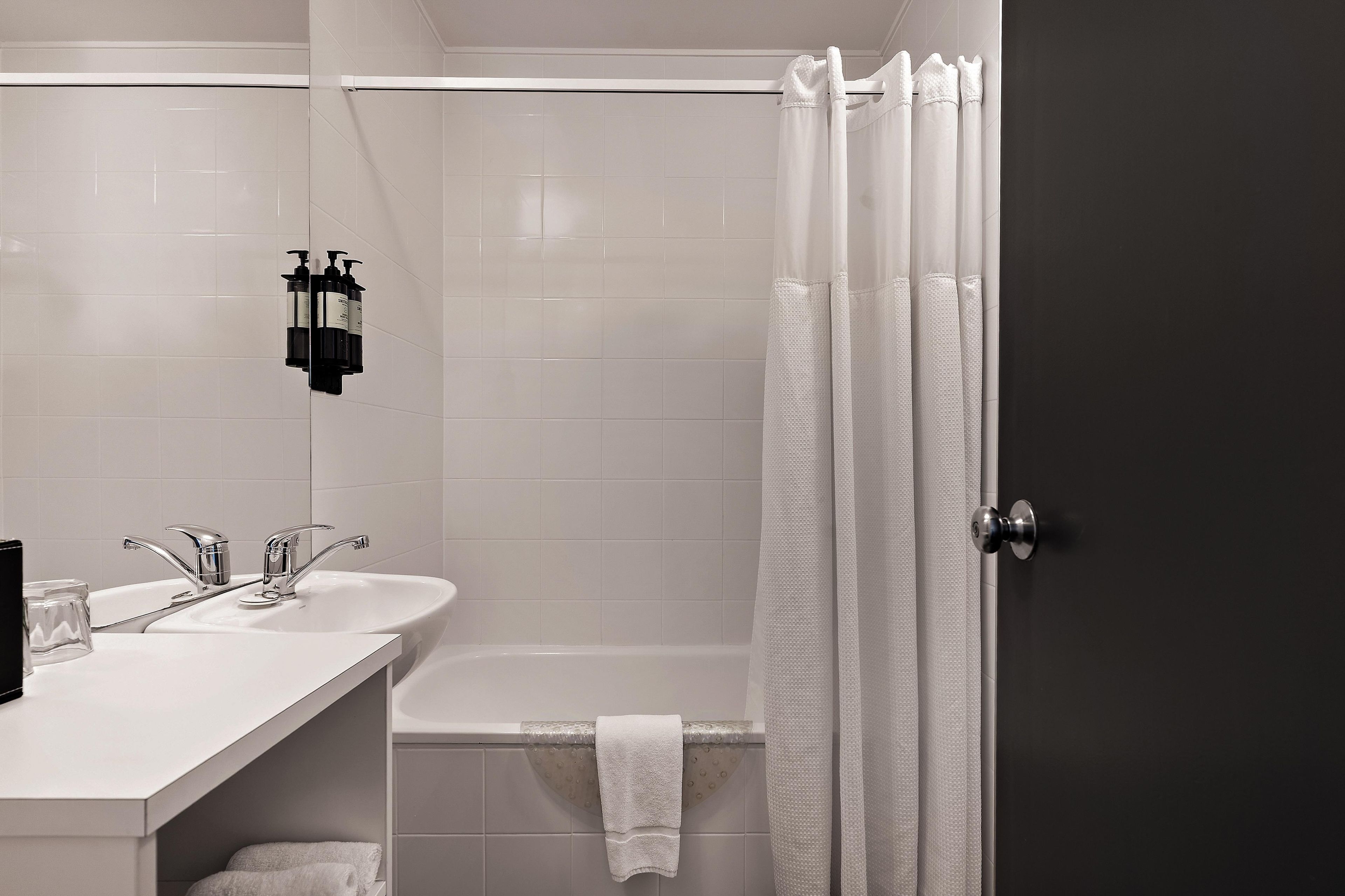 Un baño con lavamanos blanco, bañera y cortina de ducha.