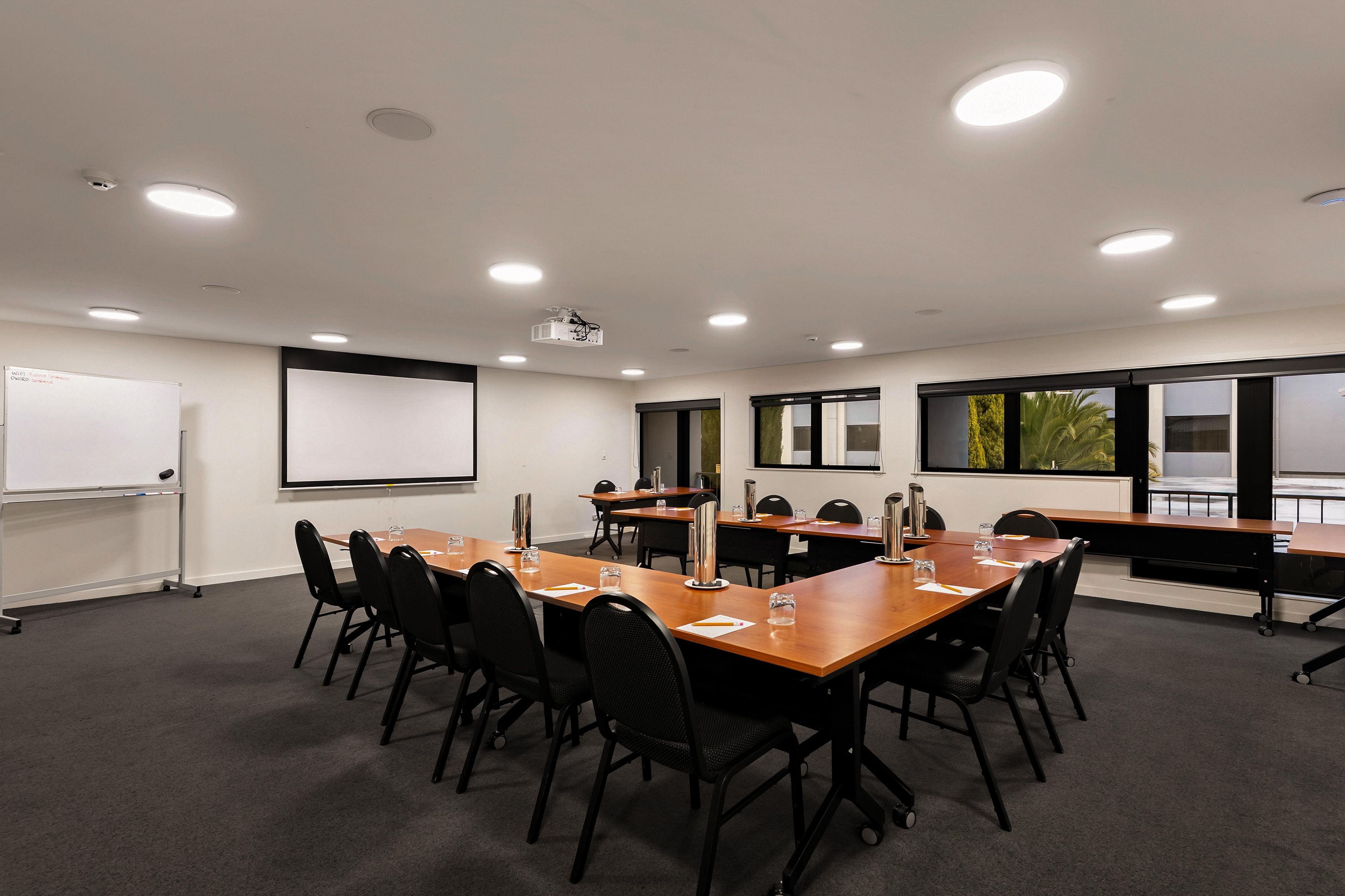A conference room with a whiteboard, projector, and multiple tables with chairs.