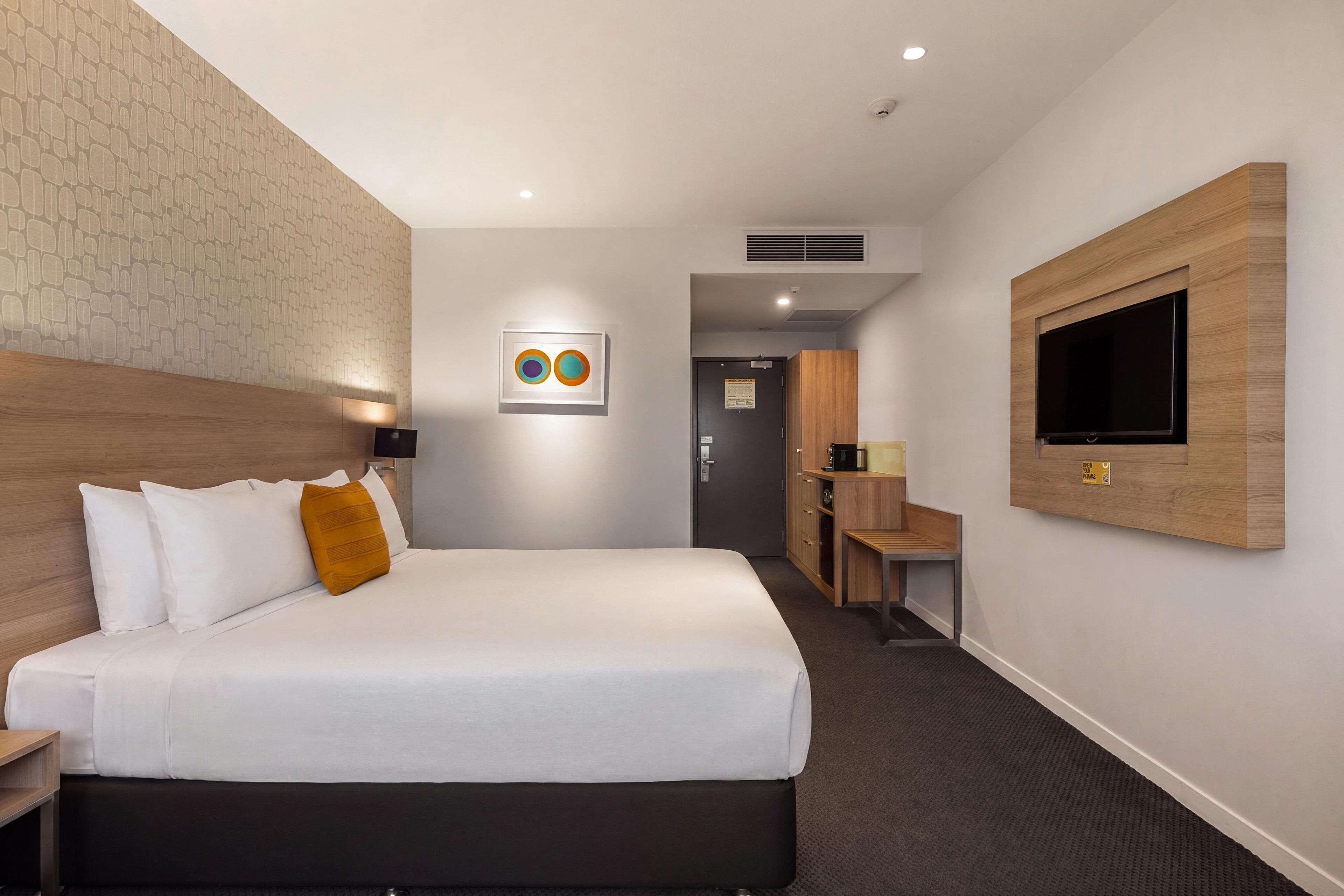 Ein Hotelzimmer mit Bett, Schreibtisch, Fernseher und Bad.