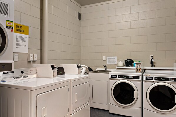 A hotel laundry room with a Maytag commercial dryer, a front-loading washing machine, and a clothes dryer. - Sudima Christchurch Airport (Christchurch)