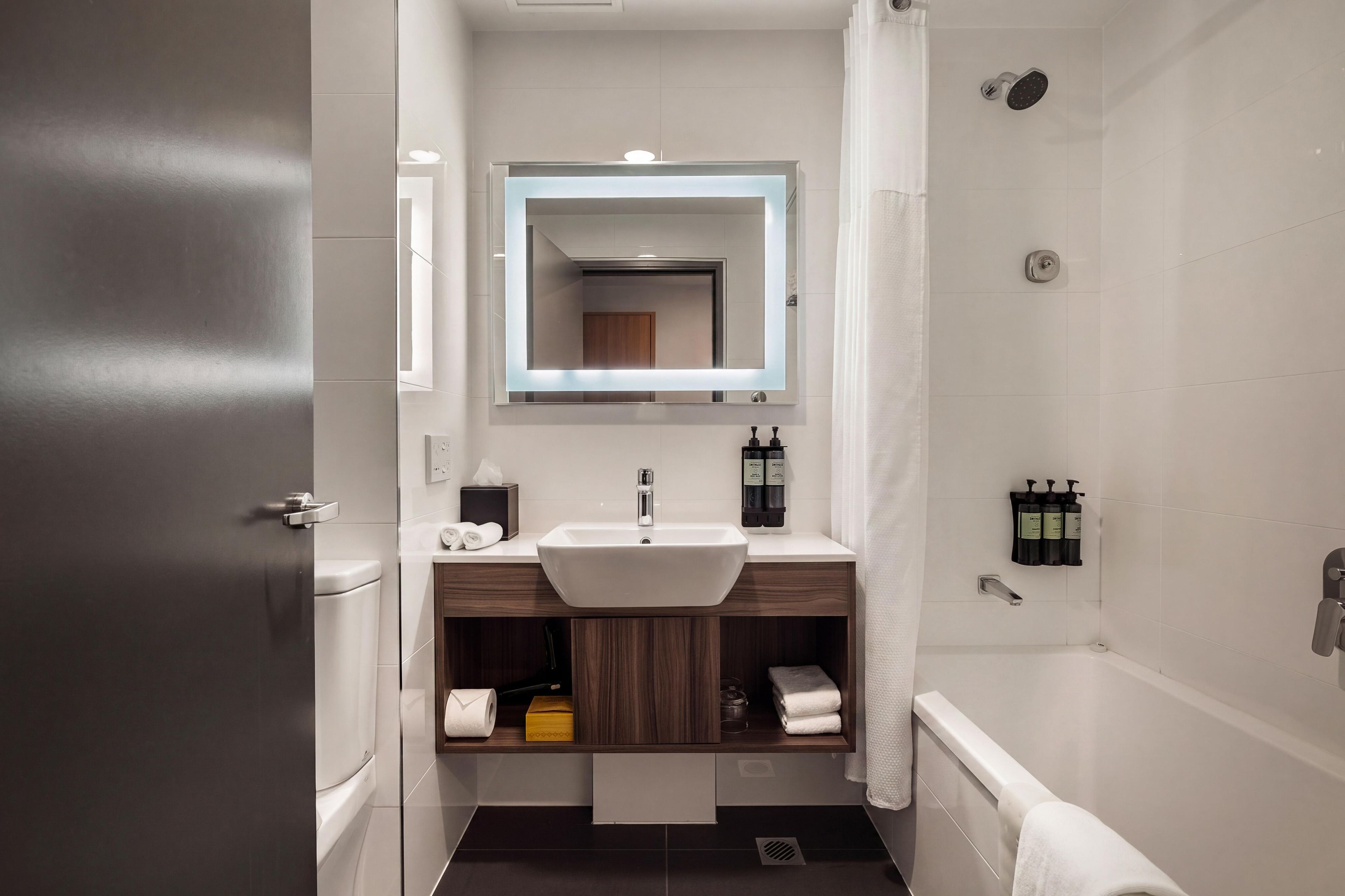 A modern bathroom with a sink, mirror, and shower.