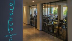 A corridor leading to a restaurant with glass doors and a sign reading "ach-eron restaurant & bar". - Sudima Christchurch Airport (Christchurch)
