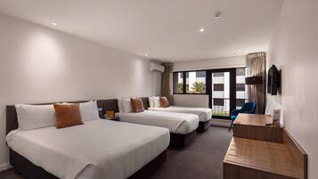A hotel room with two beds, a desk, a TV, and a window with a view.