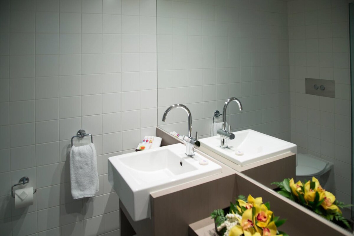 A modern bathroom with two sinks, a towel rack, and a mirror.