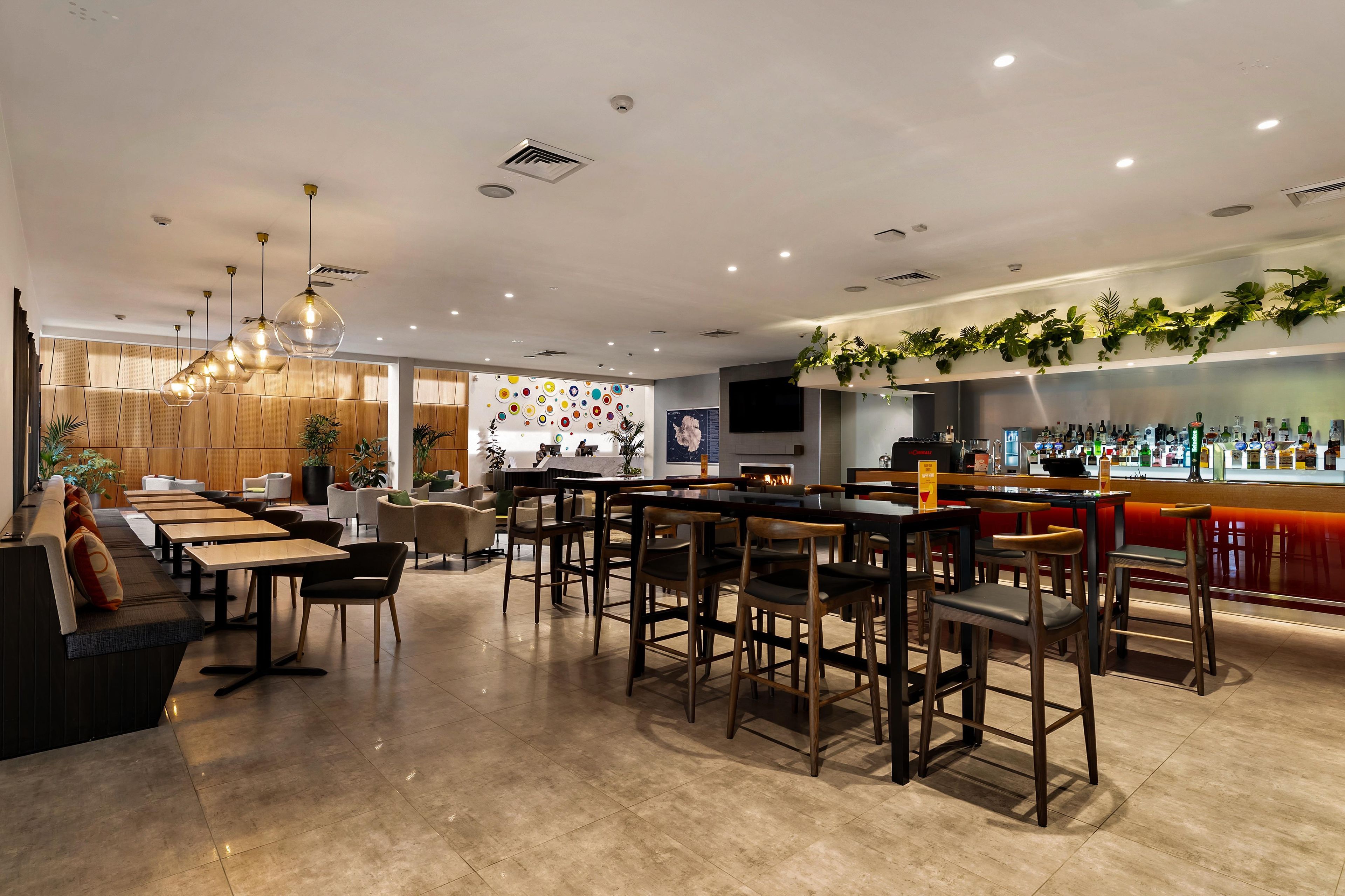 A modern bar area with a long counter, seating arrangements, and a decorative wall with circular patterns.