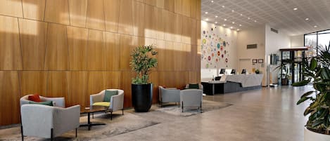 A modern reception area with a wooden panel wall, a reception desk, and several seating areas with chairs.