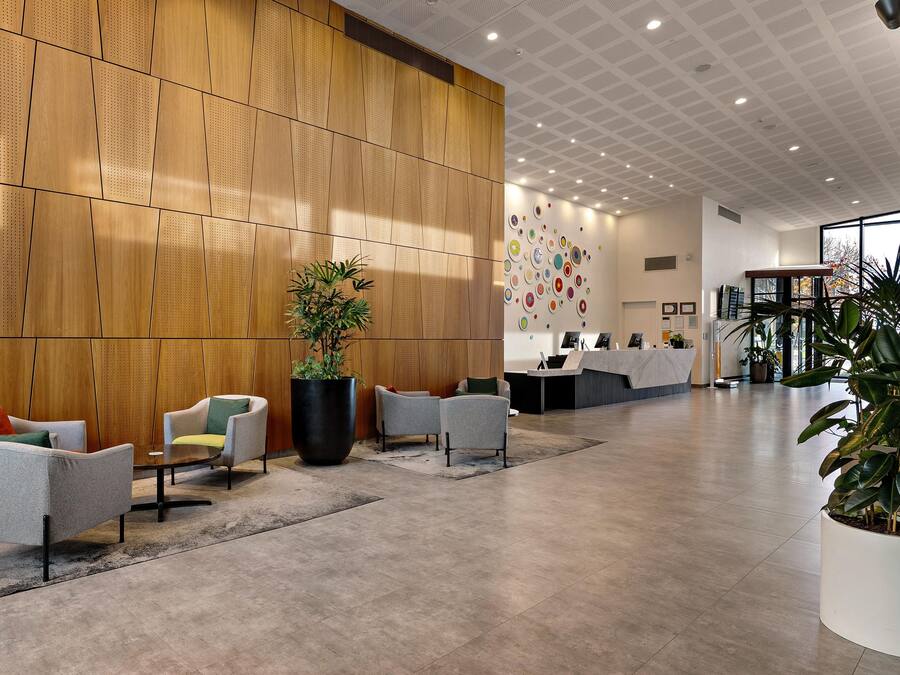 A modern reception area with a wooden panel wall, a reception desk, and several seating areas with chairs.