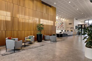 A modern reception area with a wooden panel wall, a reception desk, and several seating areas with chairs.