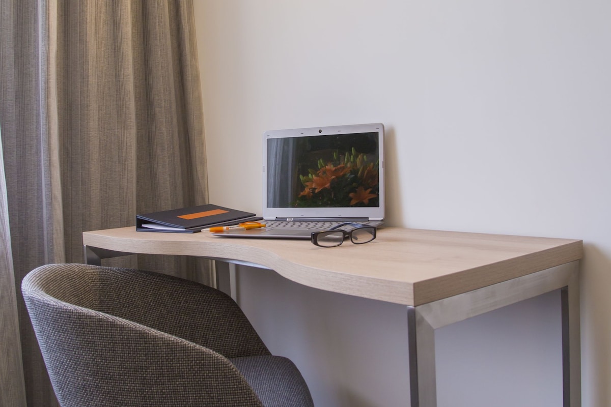 A small, modern room with a desk, a laptop, and a chair.