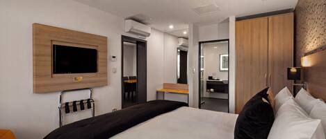 Habitación de hotel moderna con una cama grande, un televisor de pantalla plana en la pared, una mesita y un armario.