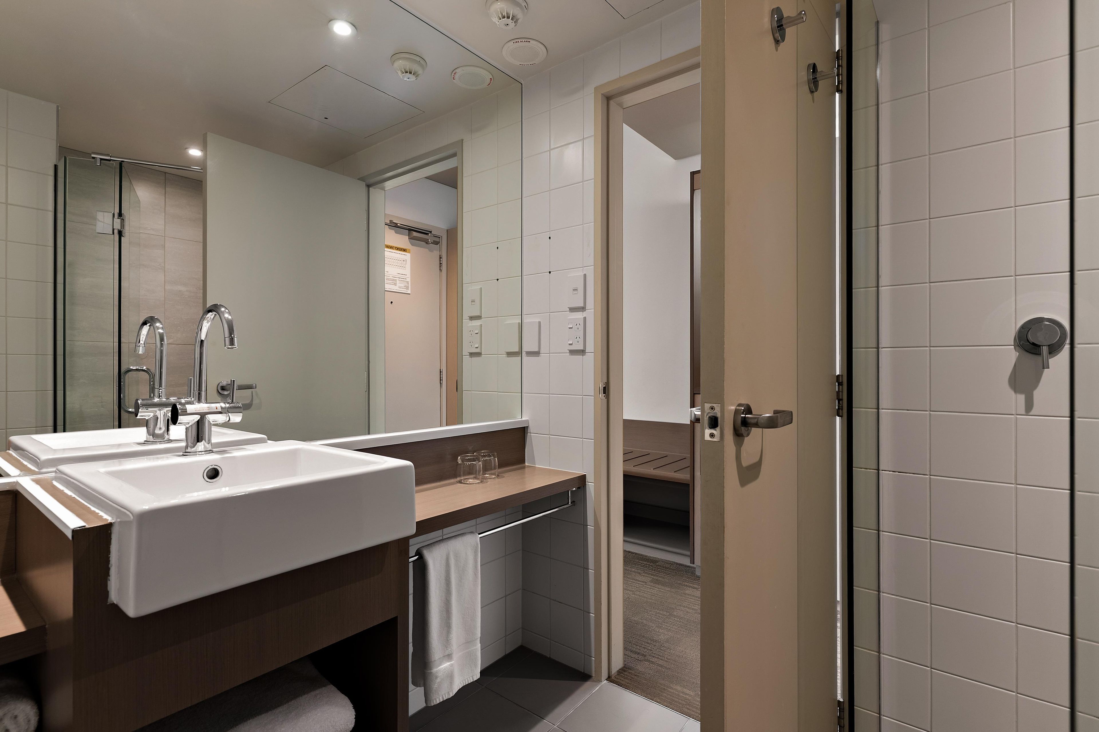 A modern bathroom with a dual sink vanity, a mirror, and a shower area.