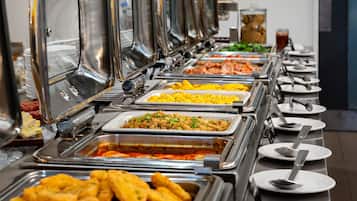 A buffet with various food options and serving utensils.