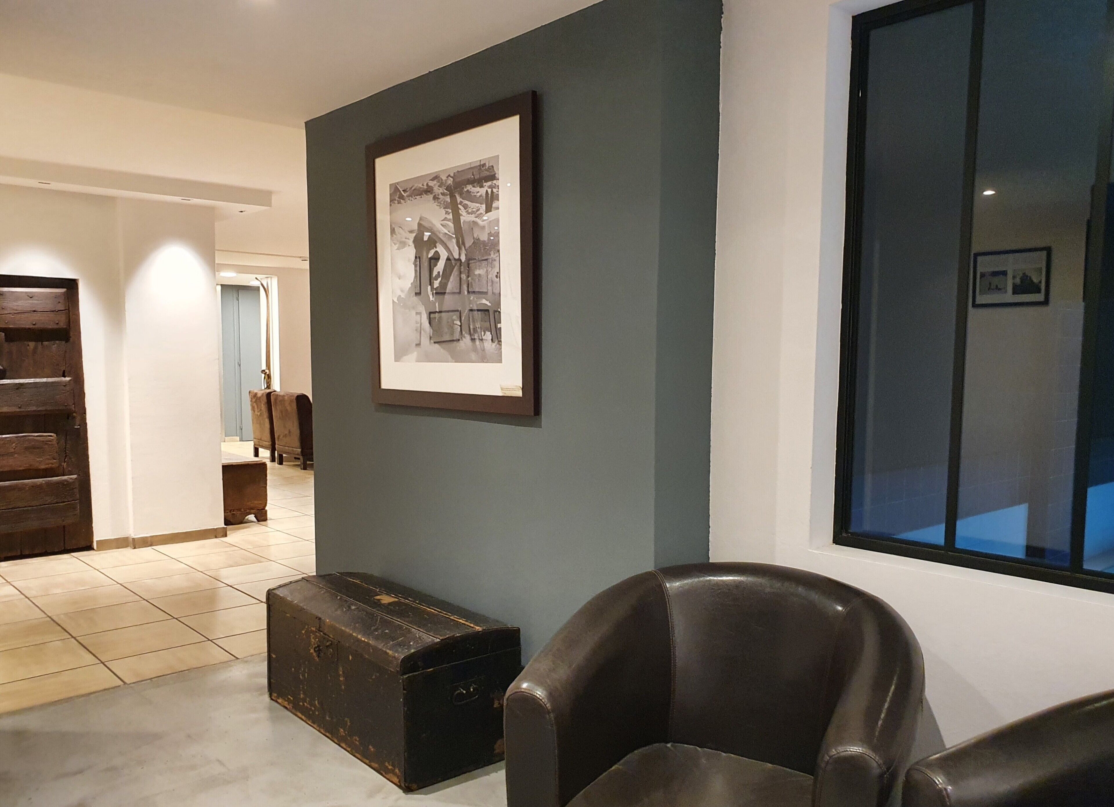 Een modern interieur met een zwart-wit foto in een lijst, een lederen fauteuil en een houten kast.