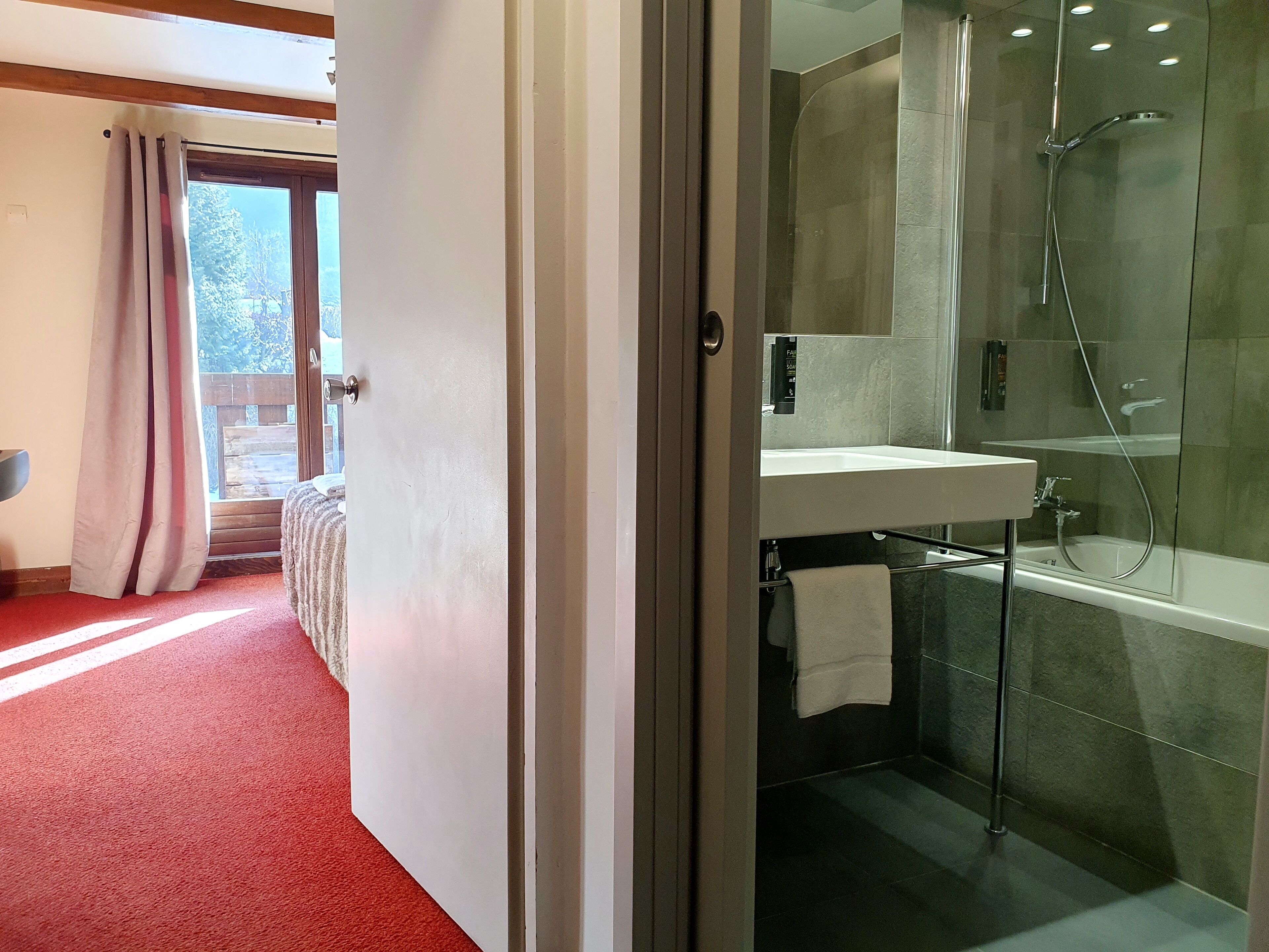Une salle de bain moderne avec une douche à parois de verre, un lavabo encastré et une serviette suspendue à un porte-serviettes.