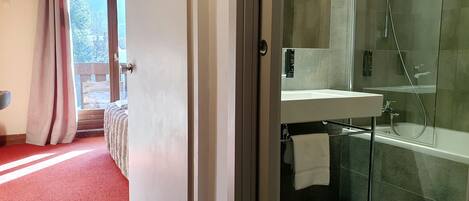 A modern bathroom with a glass-enclosed shower, a built-in sink, and a towel hanging on a rack.