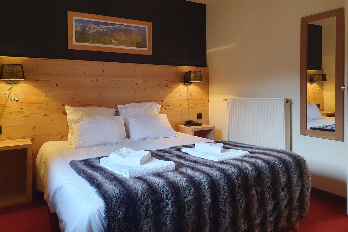 Un lit bien fait, avec du linge de lit blanc, une tête de lit en bois et un tableau accroché au-dessus.