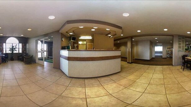A spacious lobby with a curved reception desk, tiled flooring, and a large window providing natural light. - Motel 6 Bernalillo, NM (Bernalillo)