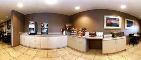 A reception area with a curved counter, cabinets, a vending machine, and a small dining area with chairs and tables.
