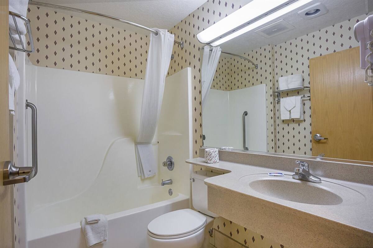 A bathroom with a bathtub, toilet, sink, and a shower curtain.