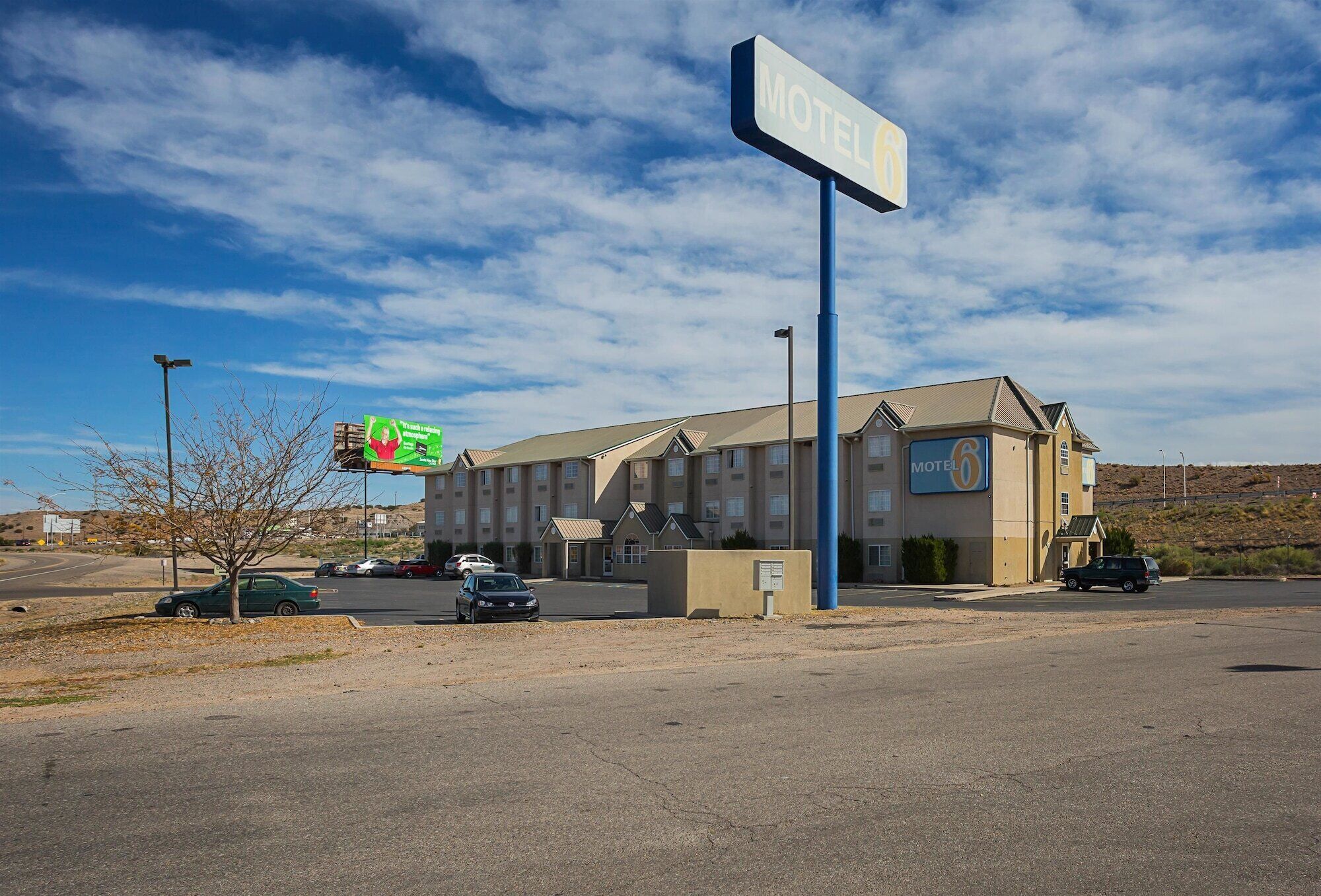 A motel with a large sign, a parking lot, and a clear sky.
