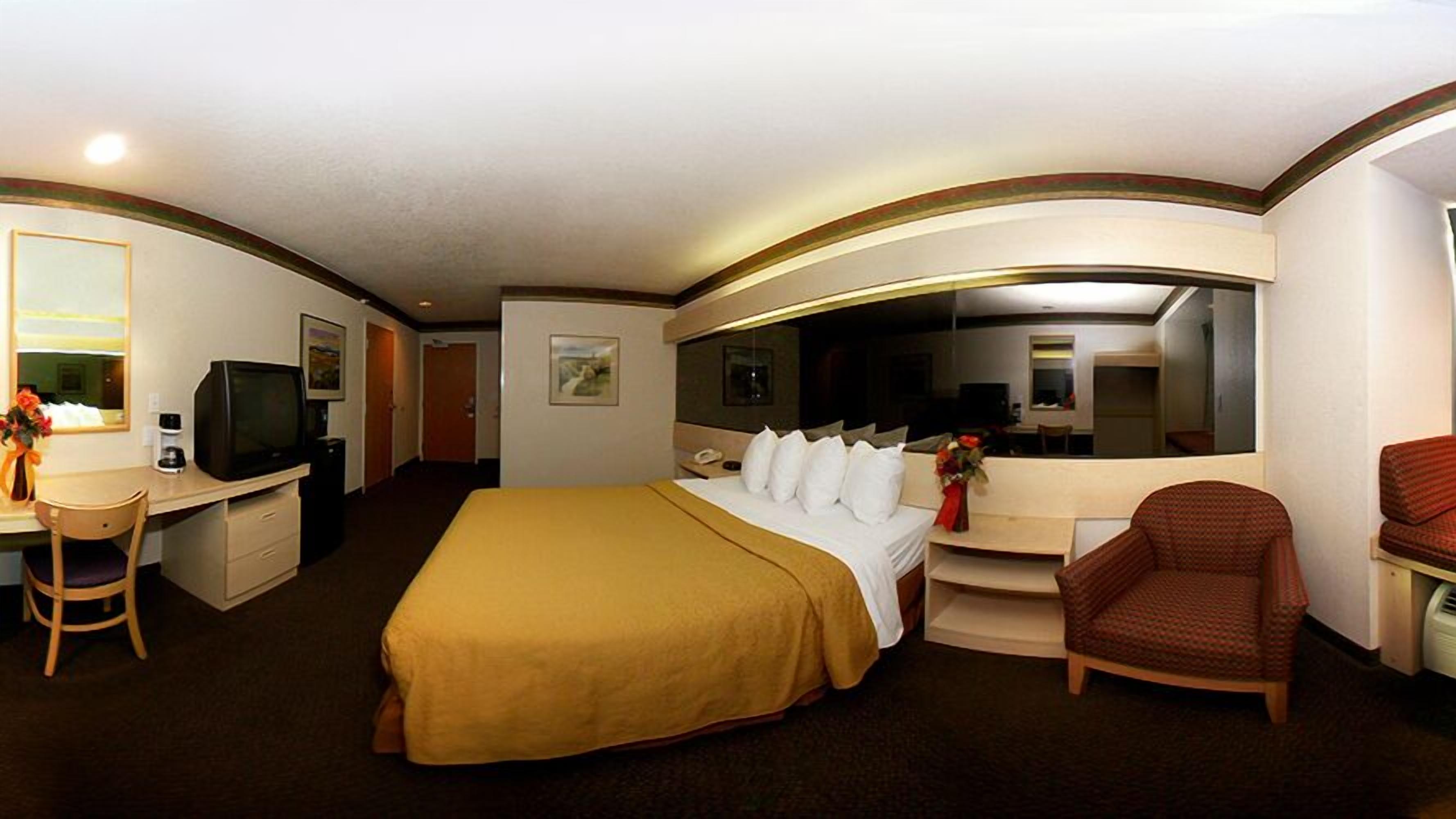 Une chambre d’hôtel avec un grand lit, un bureau avec une télévision, une chaise et un canapé.